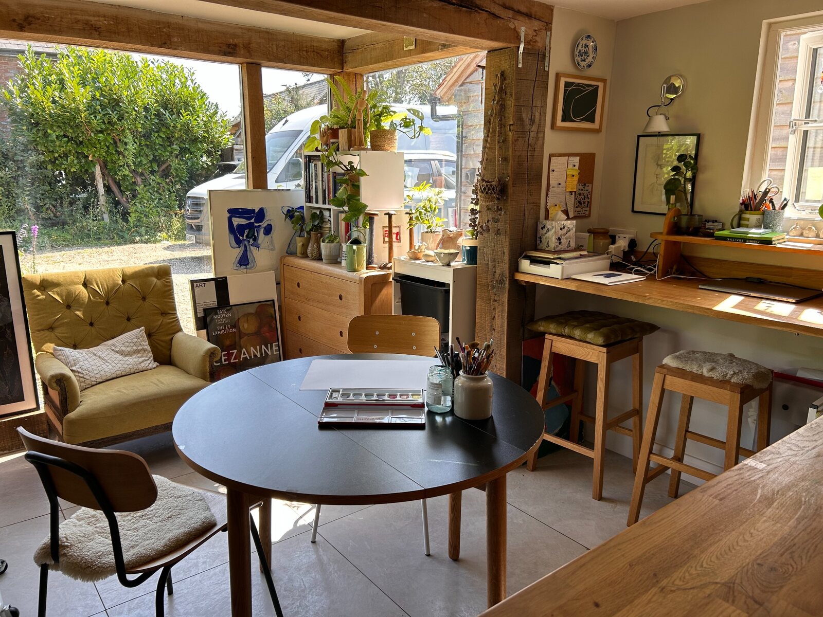 Heart Therapy art studio with a round table, watercolours, brushes, books and plants